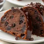 Moist Chocolate Chip Bundt Cake drizzled with chocolate glaze and topped with chocolate chips on a white plate