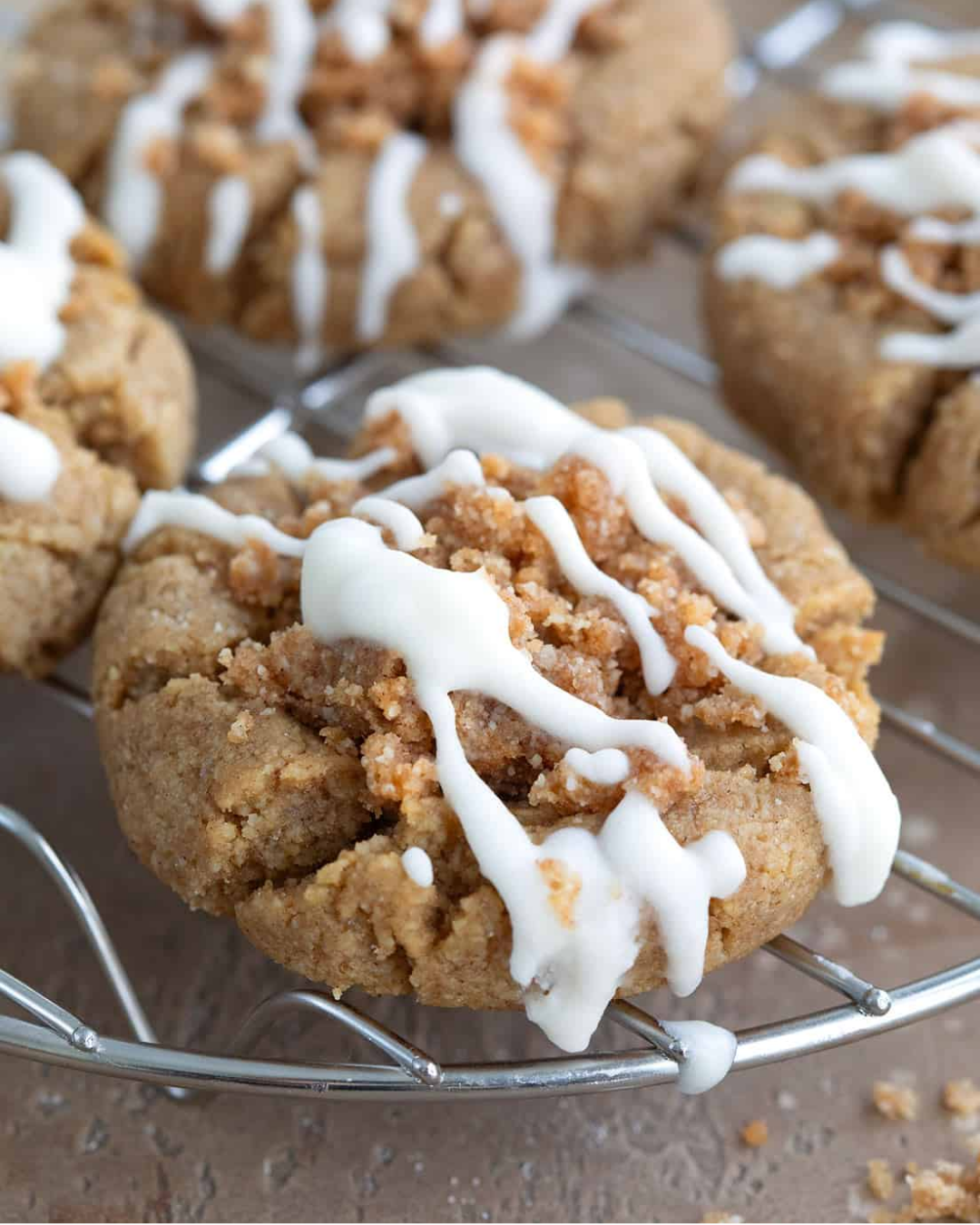 “Close-up of Keto Coffee Cake Cookies topped with cinnamon streusel and a drizzle of icing, cooling on a wire rack.”