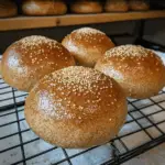 Keto bread burger buns topped with sesame seeds cooling on a wire rack